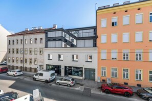 A street view with buildings, parked cars, and a clear sky. - Modern Studio | King-Size | Kitchen | Metro (Wien)