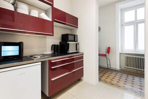 Eine kompakte Küche mit Mikrowelle, Kaffeemaschine und kleinem Kühlschrank.