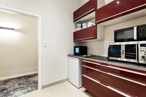 Eine kleine Küche mit Kühlschrank, Mikrowelle und Spüle.