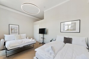 Une chambre d’hôtel moderne équipée d’un lit, d’un canapé, d’un téléviseur à écran plat et ornée d’œuvres d’art sur les murs.