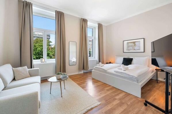 Una camera da letto moderna con un letto, una poltrona, un tavolino e una televisione.