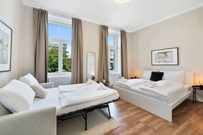 Una camera d'albergo con due letti, una grande finestra, uno specchio e un quadro appeso al muro.