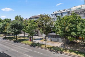 Una vista di strada con una fila di alberi, un marciapiede e un edificio dal design moderno.
