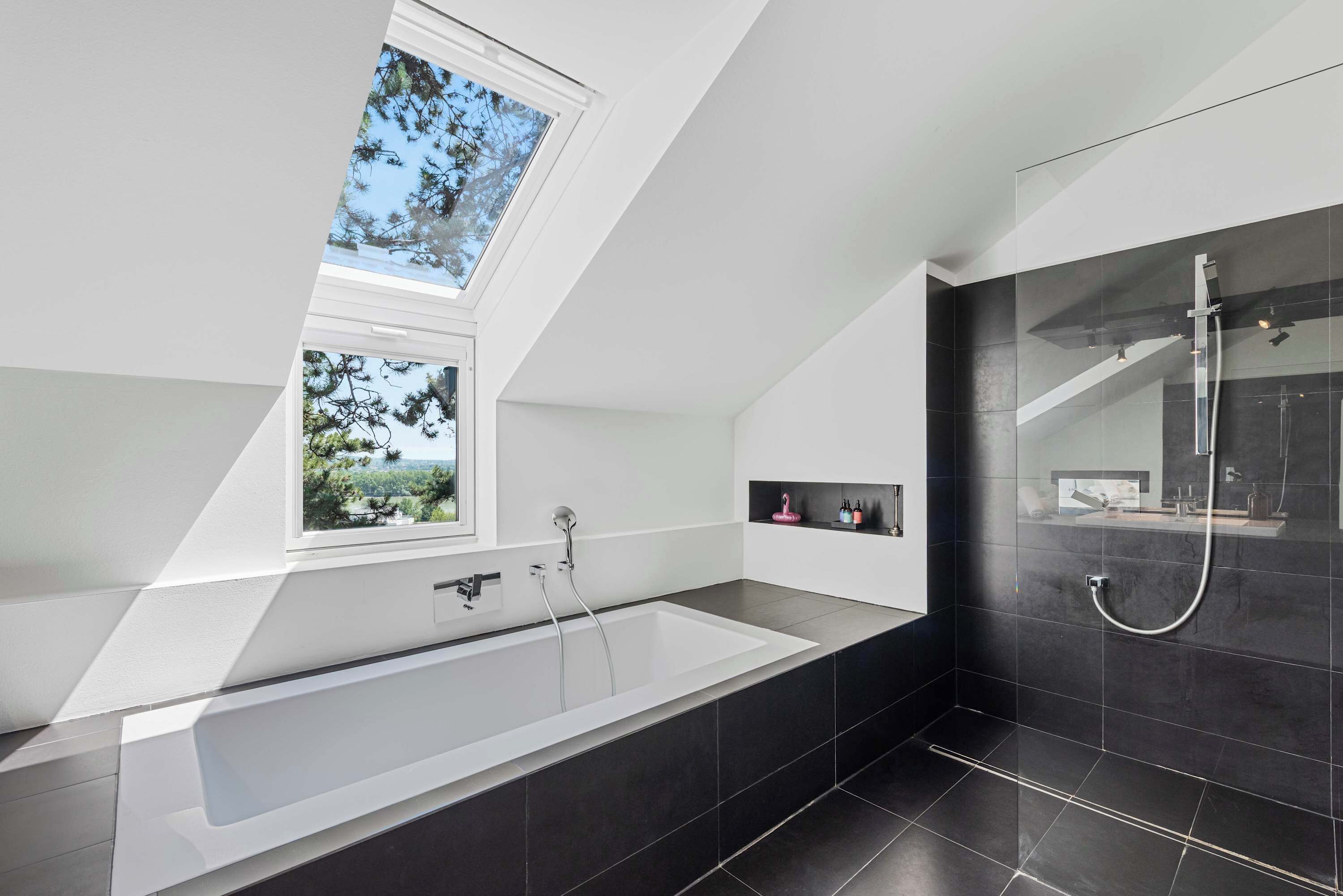 Une salle de bain moderne dotée d’une lucarne, d’une baignoire sur pieds et d’un espace douche séparé.