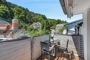 Een balkon met een tafel en stoelen, een uitzicht op een bouwplaats, en een huis op de achtergrond.