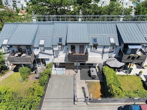 Un moderno edificio residencial con varios balcones, una zona de estar exterior cubierta y un jardín cuidado.