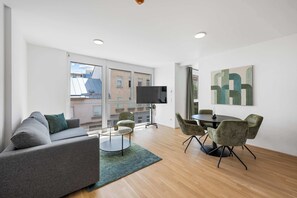 A modern living room with a sofa, a coffee table, and a dining area with chairs. - AufLeeben Vienna | Kitchen | King-Size | Metro (Wien)