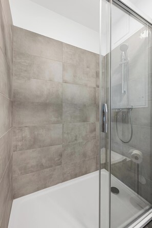 A modern shower enclosure with a glass door and a handheld showerhead. - AufLeeben Vienna | Kitchen | King-Size | Metro (Wien)