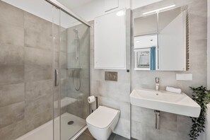 A modern bathroom with a glass-enclosed shower, a toilet, a sink, and a mirror. - AufLeeben Vienna | Kitchen | King-Size | Metro (Wien)