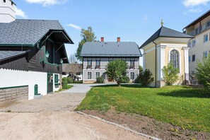 Un bâtiment de style européen traditionnel, doté d’un toit en pente, de fondations en pierre et d’un petit jardin agrémenté de pelouse et de fleurs.