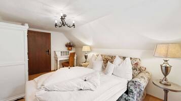 A bedroom with a bed, a chair, a nightstand, a lamp, and a ceiling light fixture.