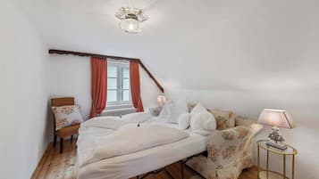 A bedroom with a bed, a chair, a table, and a lamp.