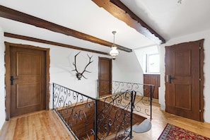 A wooden staircase with ornate metal railings, wooden doors, and a ceiling with exposed beams.