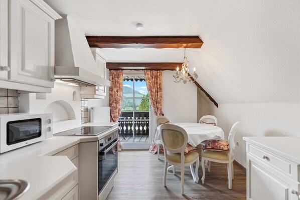 A compact kitchen with modern appliances, a dining area with a table and chairs, and a view through a window.