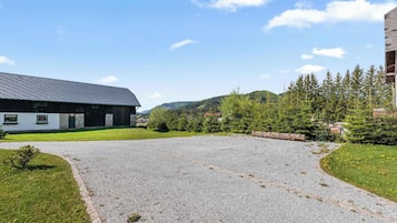A building with a sloped roof and a gravel driveway leading to a grassy area.