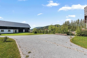 A building with a sloped roof and a gravel driveway leading to a grassy area.