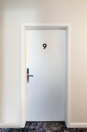 A white door with a numeric keypad lock, positioned in a hallway with a carpeted floor. - Kaiser 1BR | Metro & Tram | Nespresso | Central (Wien)
