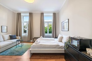 A modern hotel room with a bed, a sofa, a TV, and a view of the city. - Kaiser Room | King Bed | Metro & Tram (Wien)