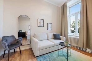 A modern living room with a sofa, armchair, and a coffee table. - Kaiser Room | King Bed | Metro & Tram (Wien)
