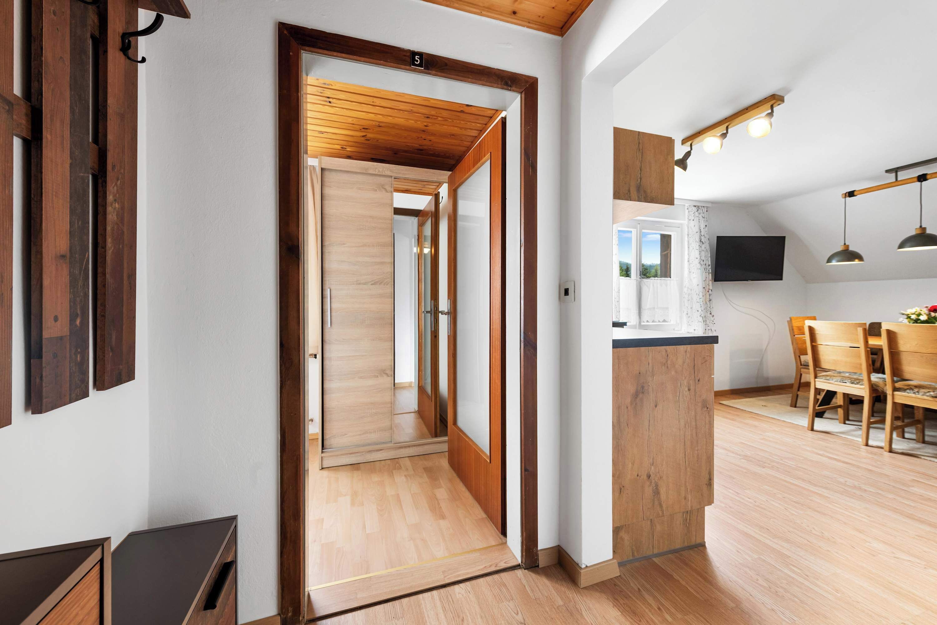 Ein modernes Interieur mit Holzboden, einer Küchenzeile mit Essplatz und einem großen Fenster mit Blick.