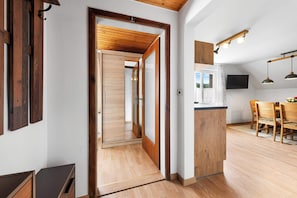 Un interno moderno con pavimento in legno, angolo cottura con tavolo e sedie, e un'ampia finestra che offre una vista.