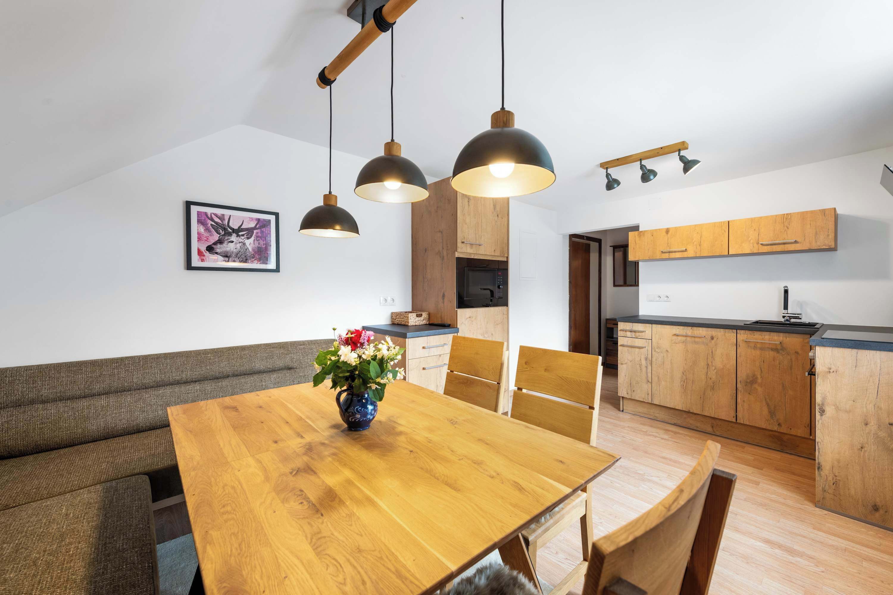 Una cucina moderna con mobili in legno, un tavolo da pranzo con sedie e illuminazione a sospensione.