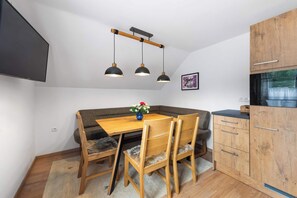 A compact kitchen with a dining area, wooden cabinets, and a modern pendant light fixture.