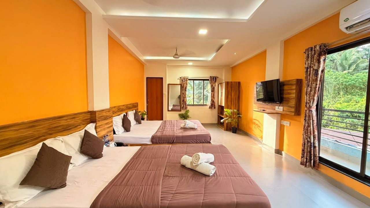 A hotel room with two beds, a television, and a window with curtains.