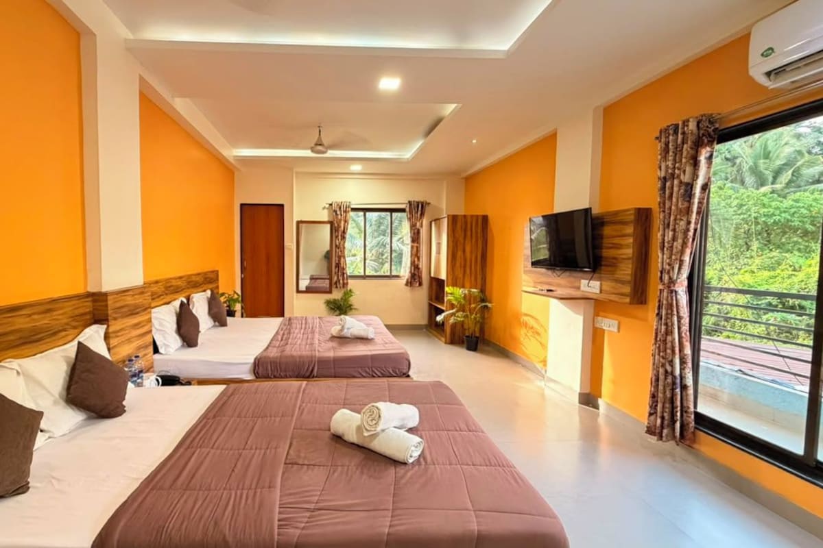 Habitación de hotel con dos camas, televisor y ventana con cortinas.