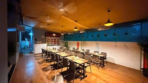A dining area with wooden flooring, tables, chairs, and hanging pendant lights. - Lotus - The Beach Resort  (Nagaon)