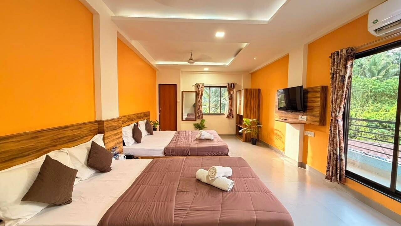 Habitación de hotel con dos camas, televisor y ventana con cortinas.