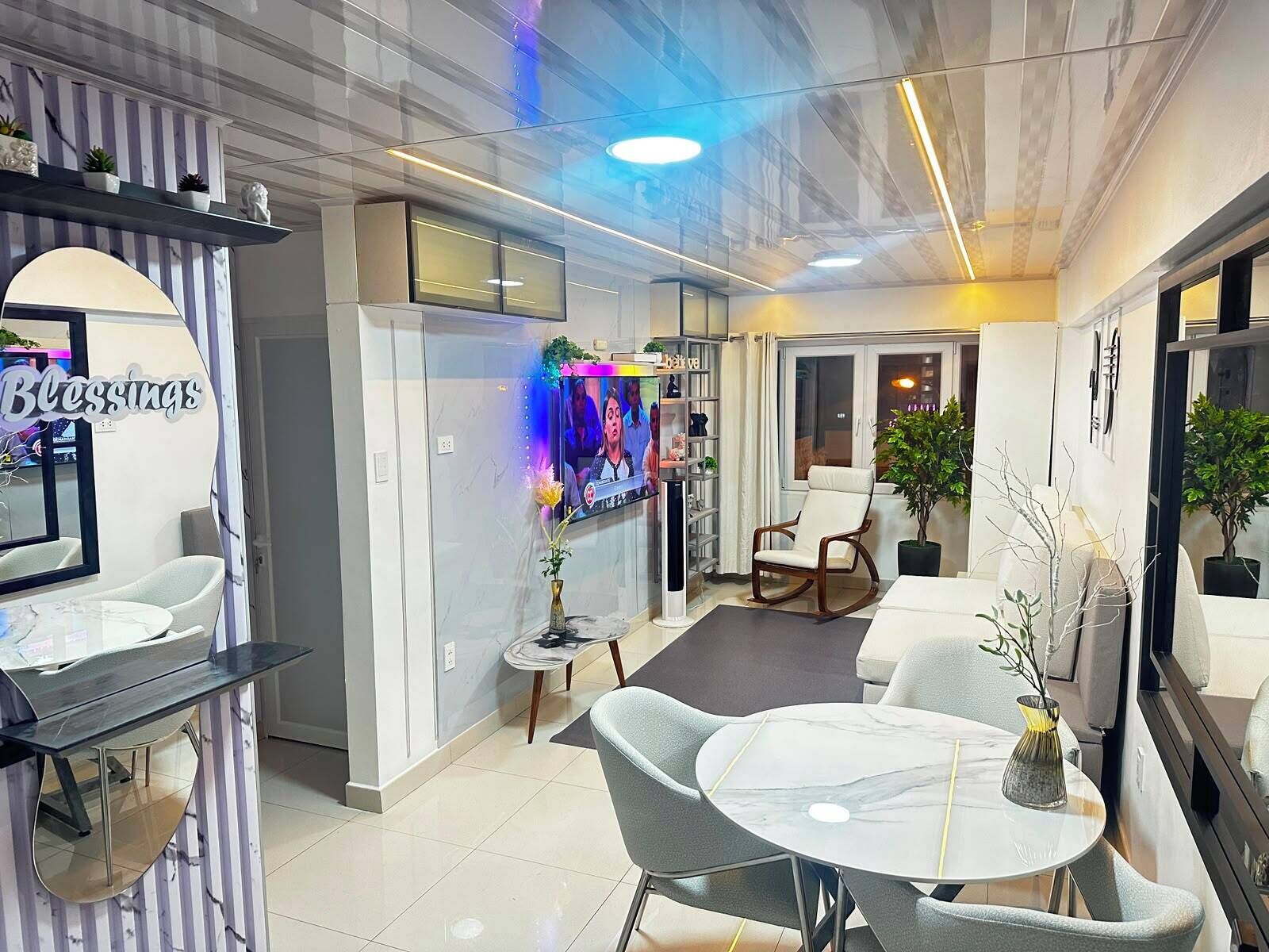 A modern interior with a reception desk, seating area, and a television displaying a program.