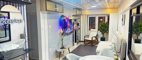 A modern interior with a reception desk, seating area, and a television displaying a program.