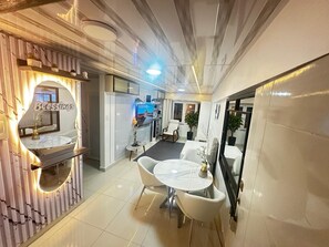 Un interior moderno con una mesa de comedor redonda, sillas blancas, una pequeña barra y un espejo que refleja la habitación.