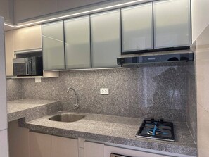 Eine moderne Küche mit Granit-Arbeitsplatte, Edelstahl-Spüle und Gasherd.