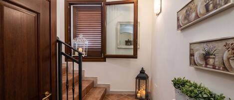 A staircase with a wooden door, a lit lantern, and a wall-mounted mirror.