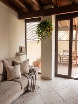 Ein modernes Wohnzimmer mit einem beigen Sofa, einer hängenden Pflanze und Blick auf die Terrasse.
