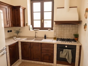 Eine Küche mit Holzausstattung, einem Doppelspülbecken, einem Gasherd und einem Fenster mit Aussicht.