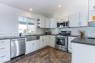 Una cocina moderna con armarios blancos, electrodomésticos de acero inoxidable y piso de madera.