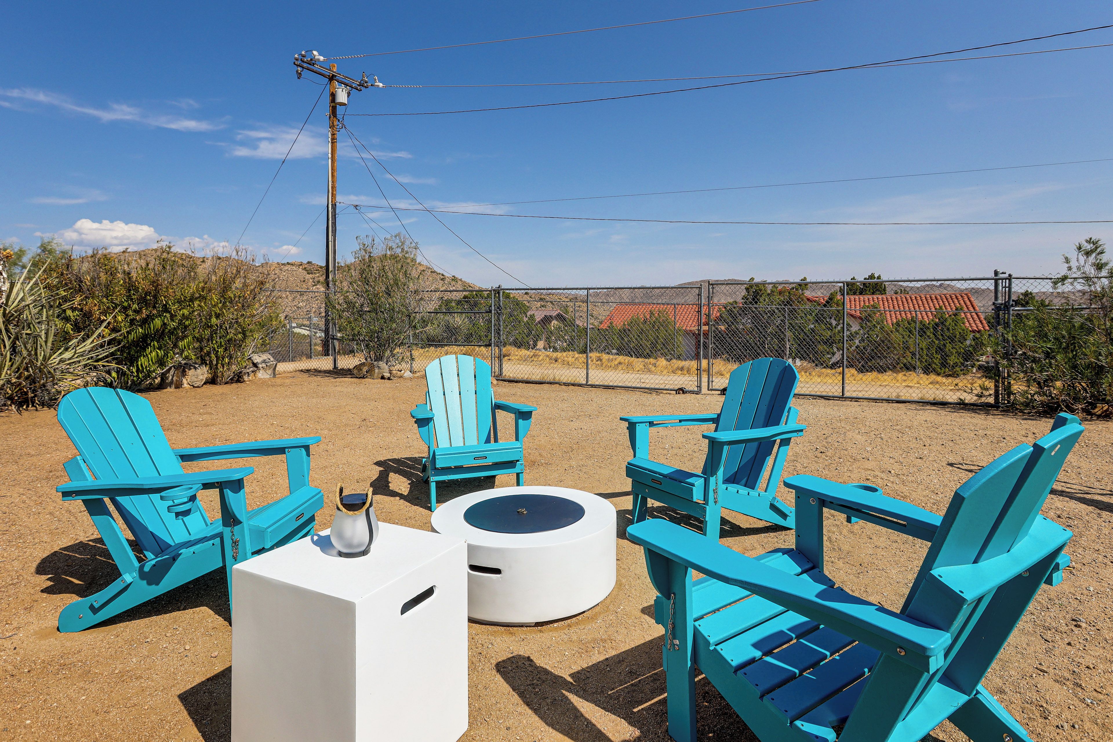 Outdoor seating with chairs and a table, surrounded by a fence and vegetation.