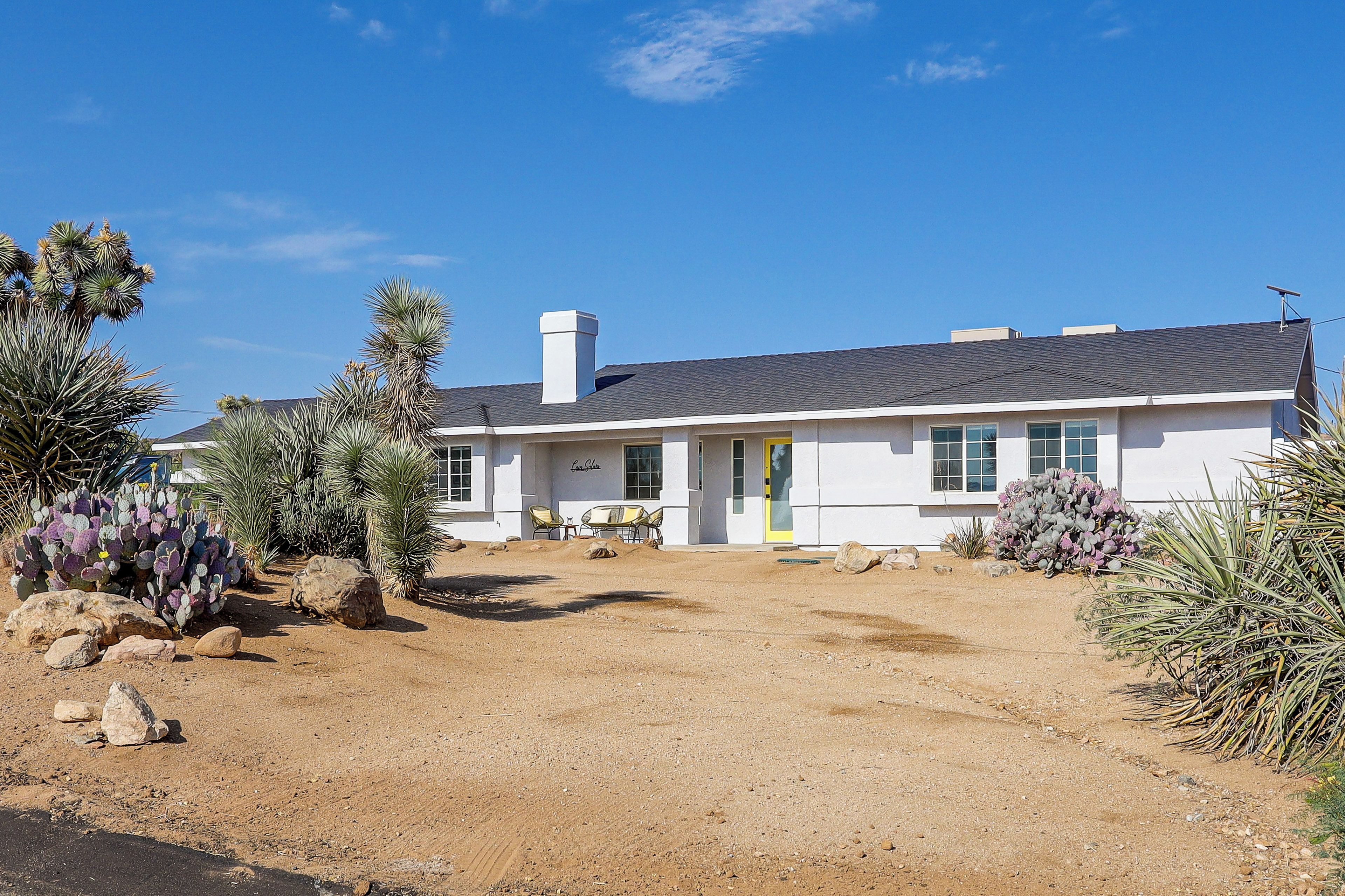 A single-story house with a front porch, a chimney, and a clear blue sky.