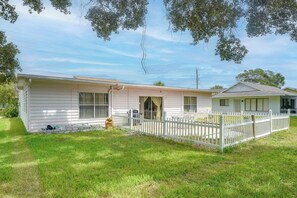 Ein Bungalow mit umzäunter Garten, kleiner Veranda und Garage.