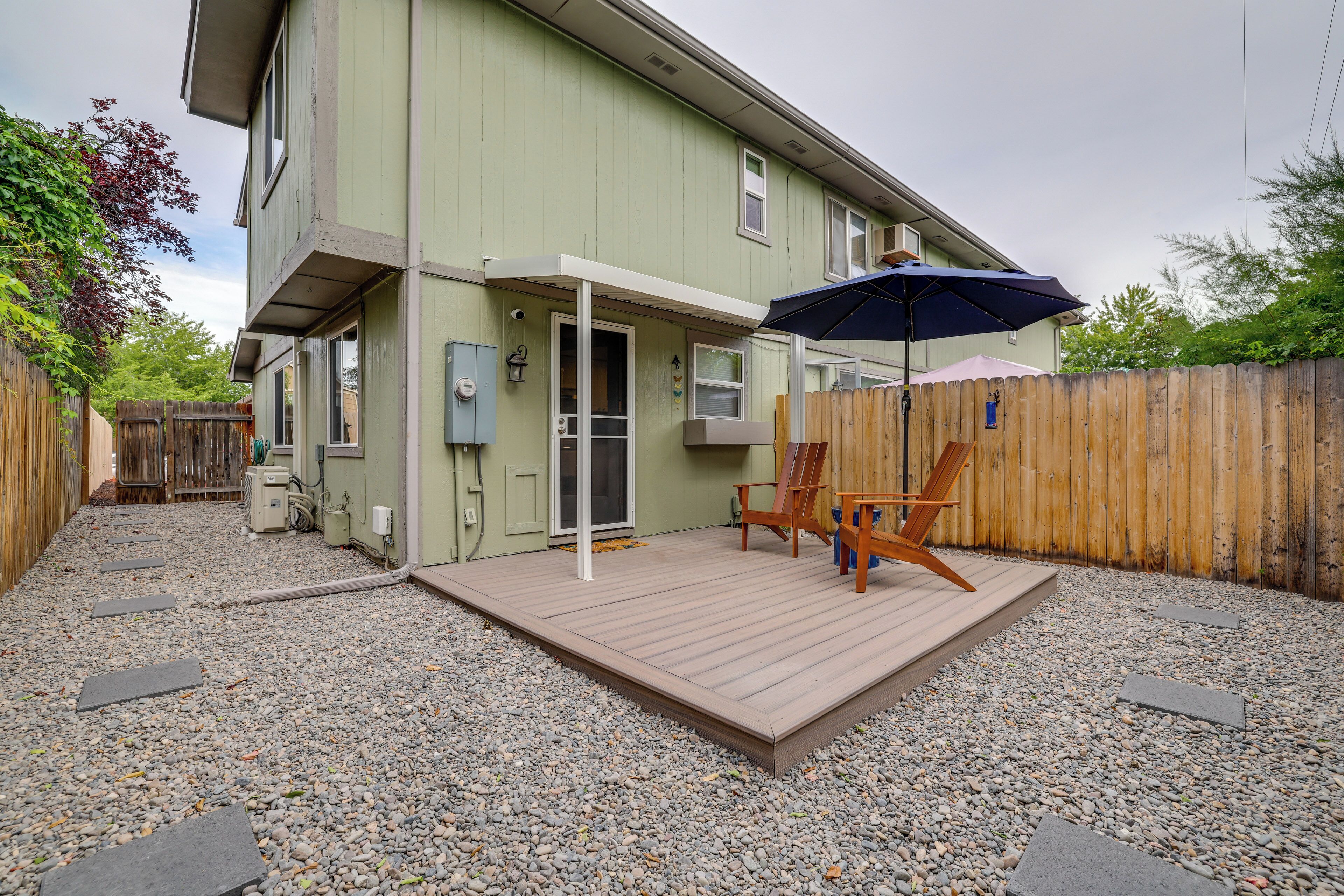 A two-story house with a covered patio area, a wooden deck, and a gravel driveway.