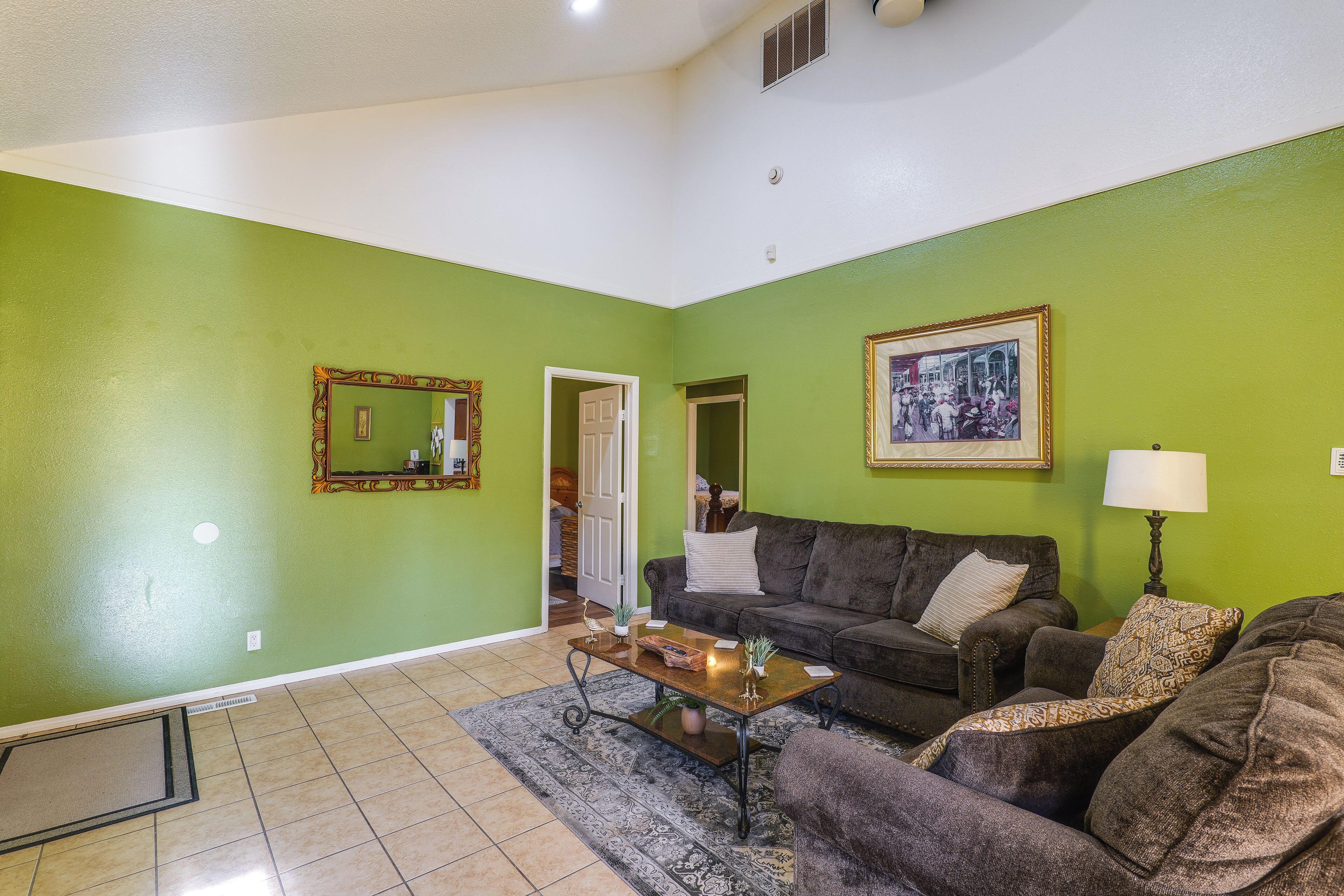 A living room with a green wall, a sofa, a coffee table, and a rug.