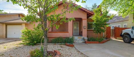A residential house with a garage, a driveway, and a well-maintained front yard with gravel and plants.