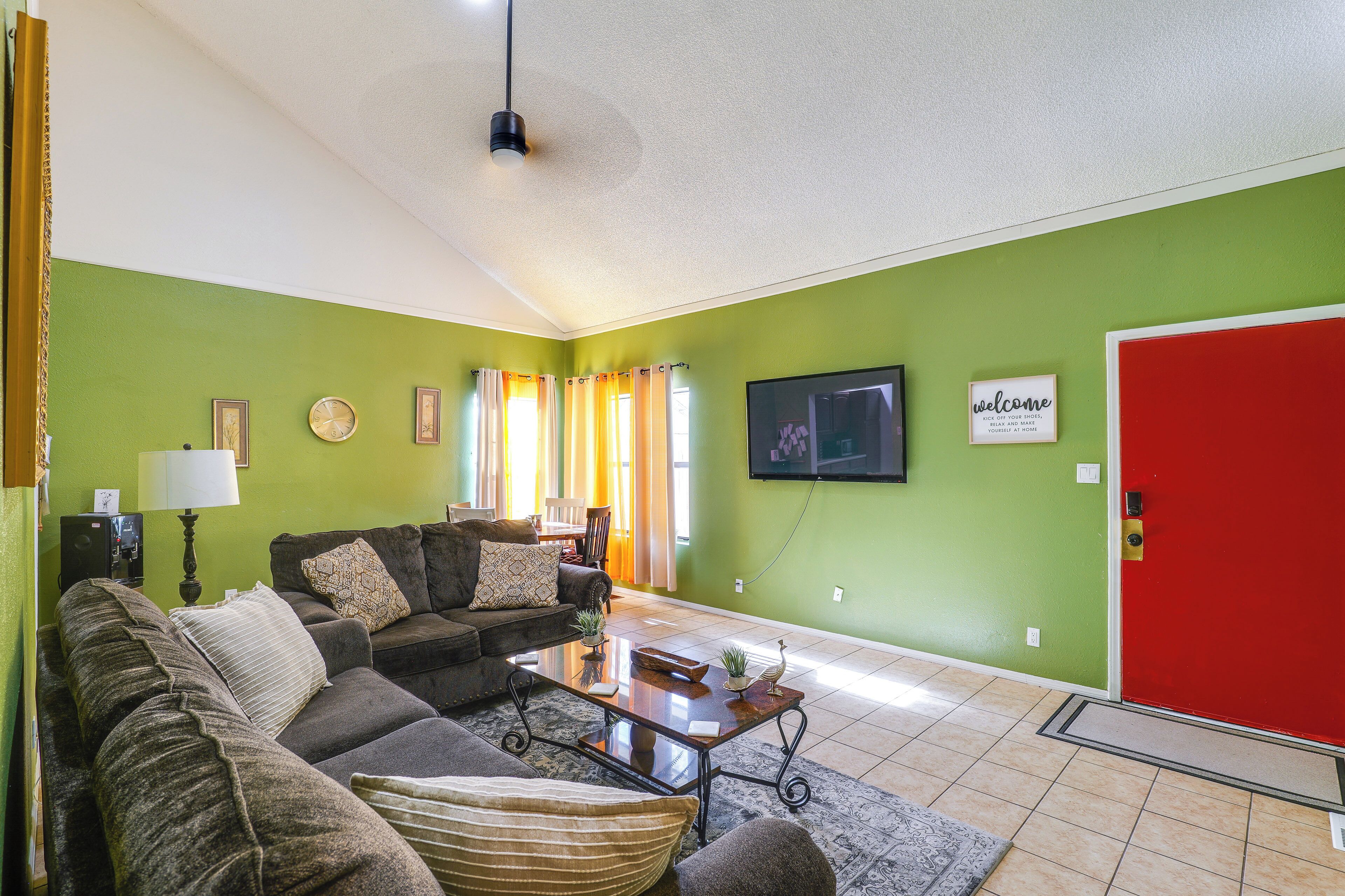 A living room with a green wall, a red door, a flat-screen TV, and a coffee table.