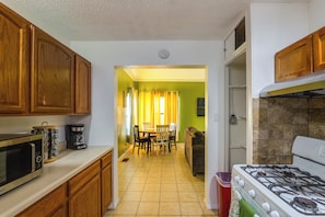 A kitchen with wooden cabinets, a stove, a microwave, and a dining area with a table and chairs.