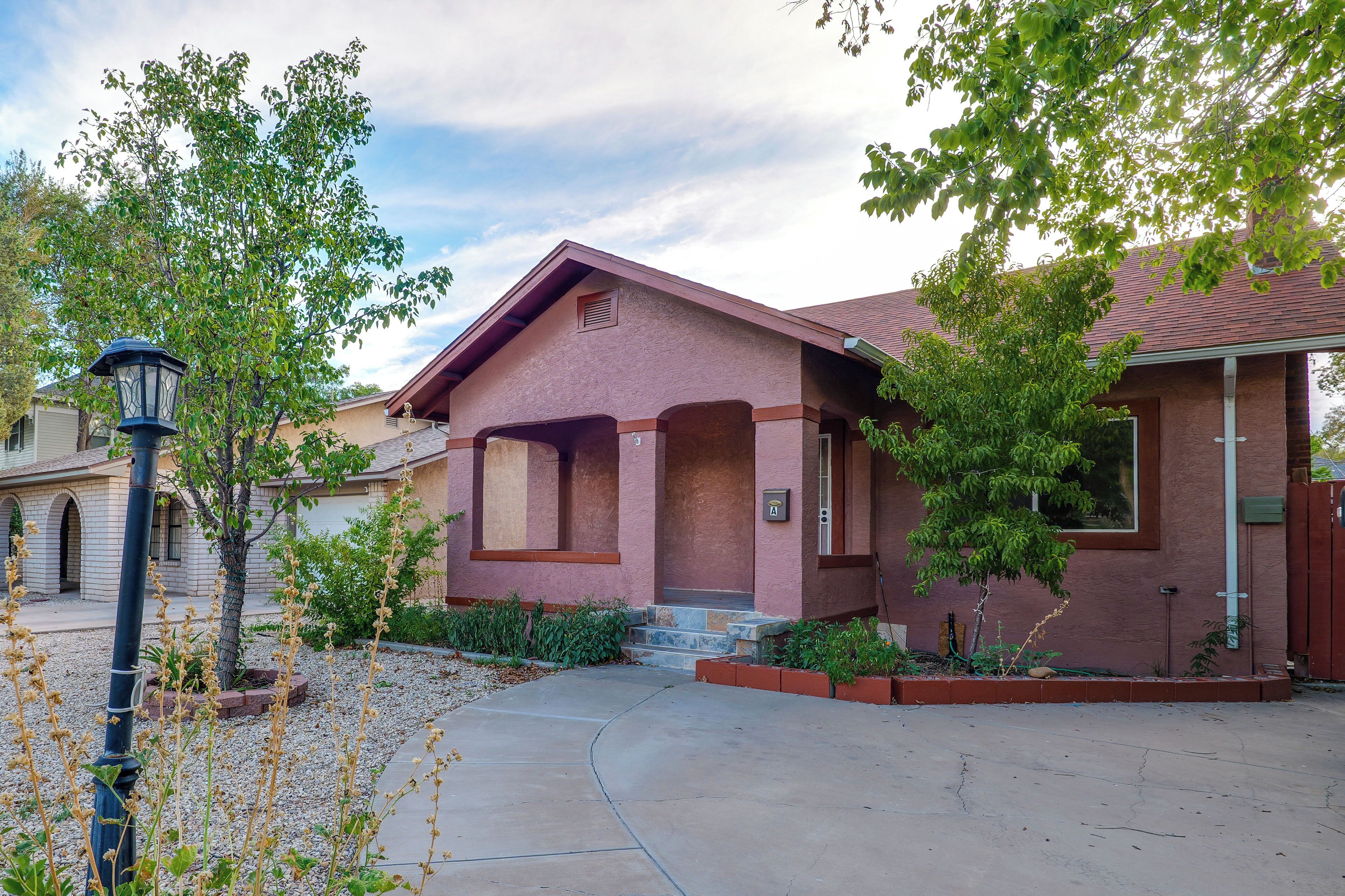 A residential building with a red facade, a front porch, and a clear sky.