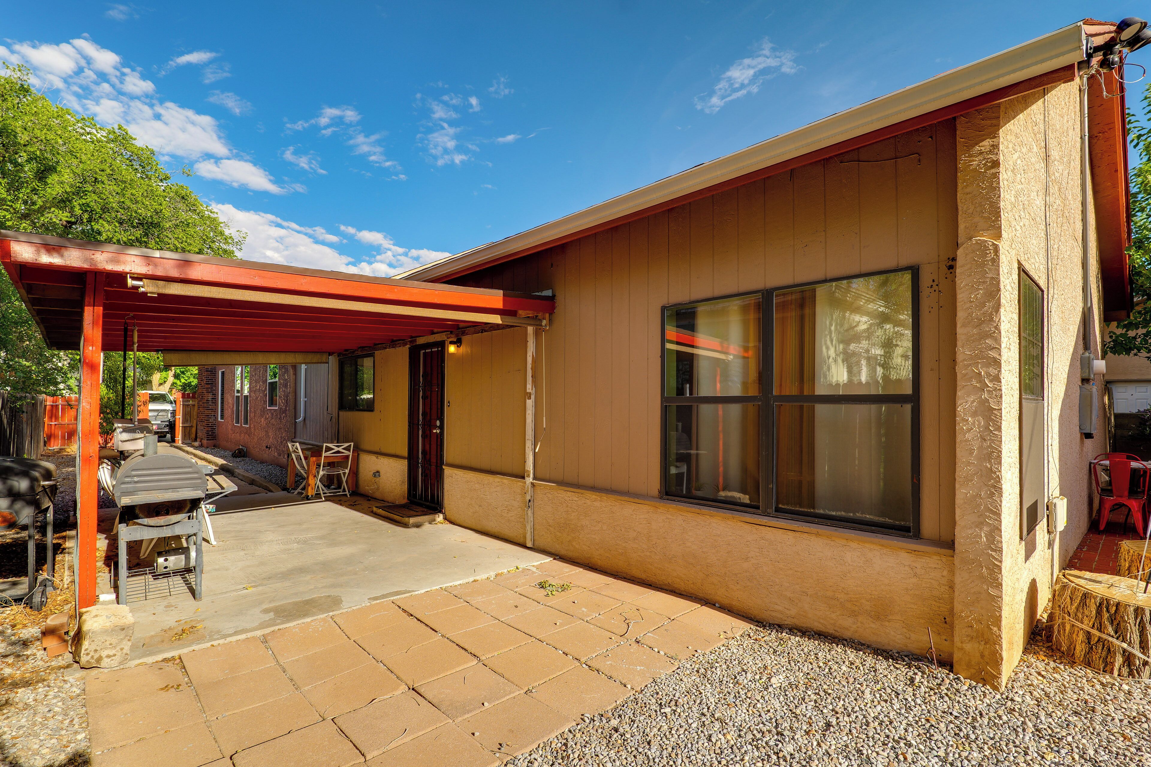A single-story building with a covered patio area, a large window, and a door.