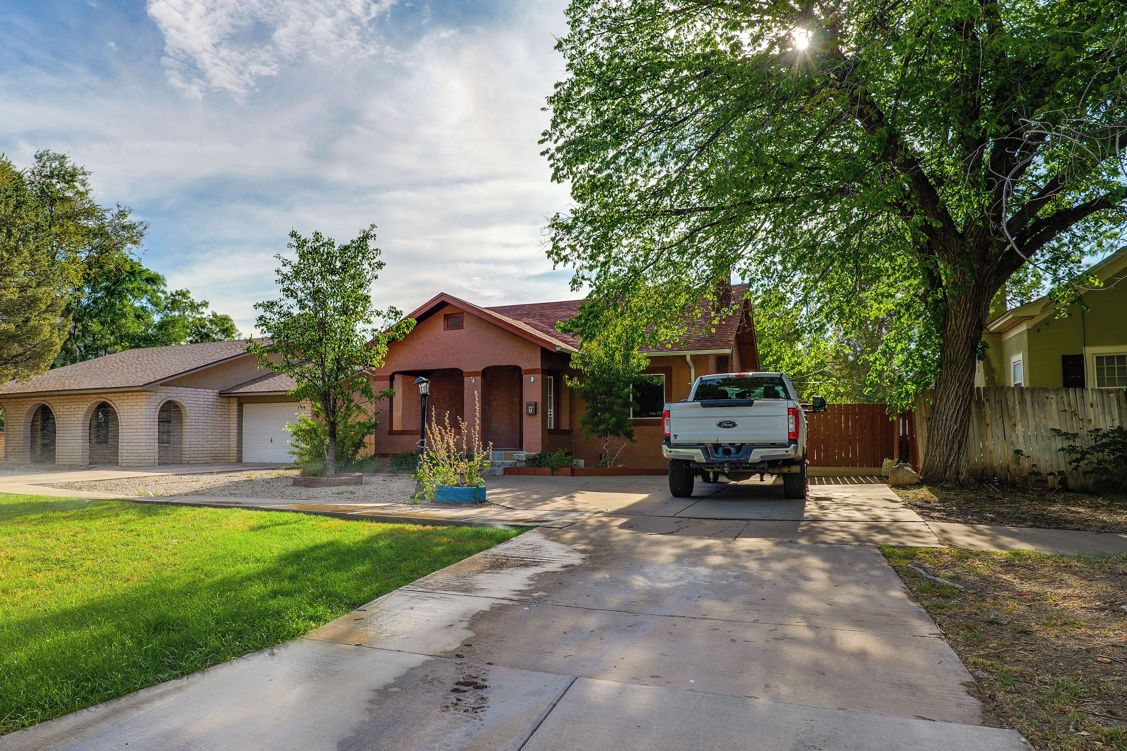 A residential driveway with a parked pickup truck, a house with a garage, and a well-maintained lawn.